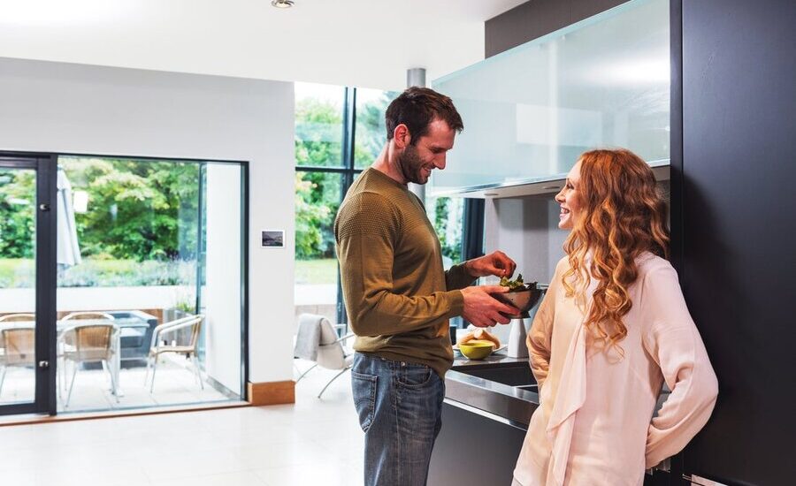 A couple chatting joyfully in their kitchen in their smart home.