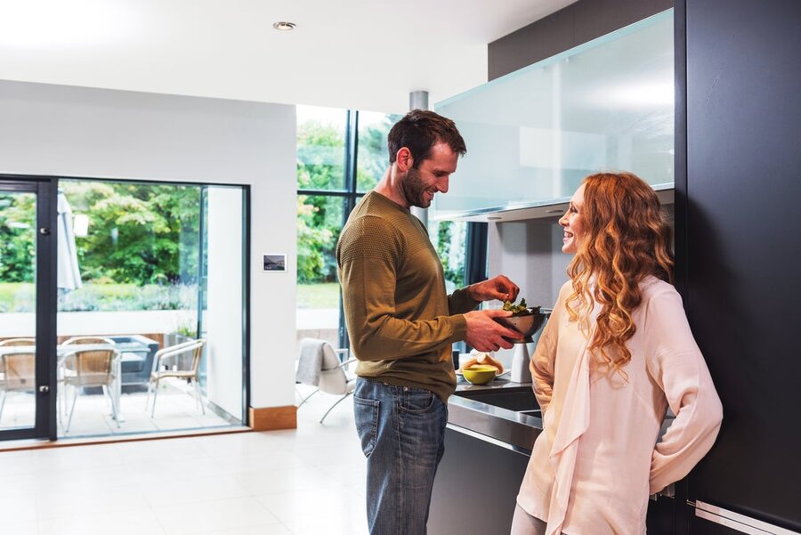 A couple chatting joyfully in their kitchen in their smart home.