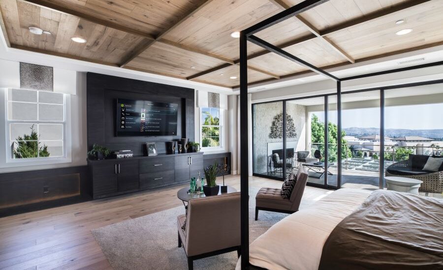 A bedroom with in-ceiling speakers and the Control4 platform displayed on the TV.
