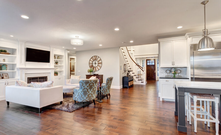 Beautiful living space pictured from the kitchen with a living room and staircase beyond, featuring entertainment aspects and recessed lighting.