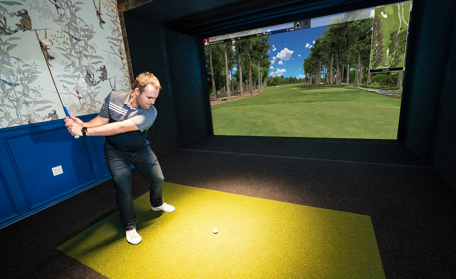 A man swinging a golf club by using a golf simulator